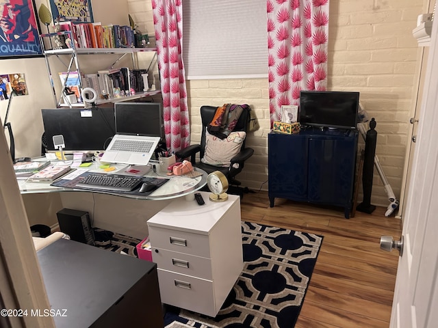 office with brick wall and hardwood / wood-style floors