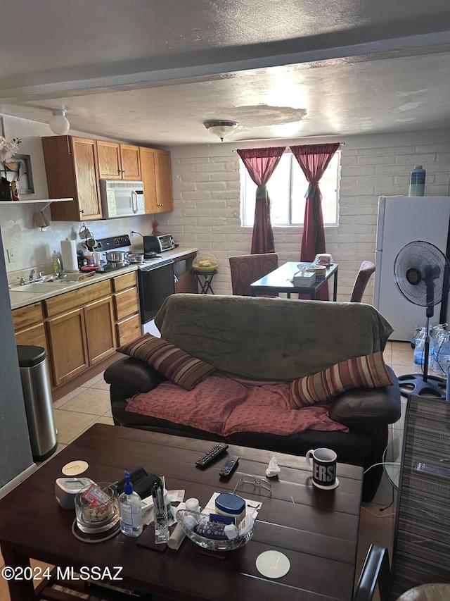 tiled living room featuring sink, washer / dryer, and brick wall