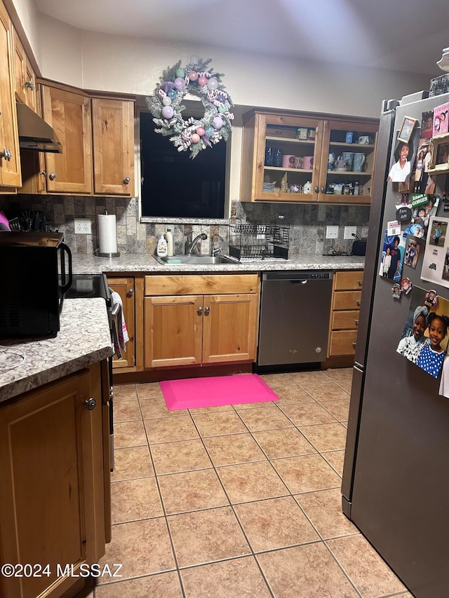 kitchen featuring appliances with stainless steel finishes, sink, backsplash, light tile patterned floors, and light stone counters