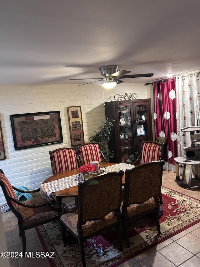 dining room featuring tile patterned floors, ceiling fan, and brick wall