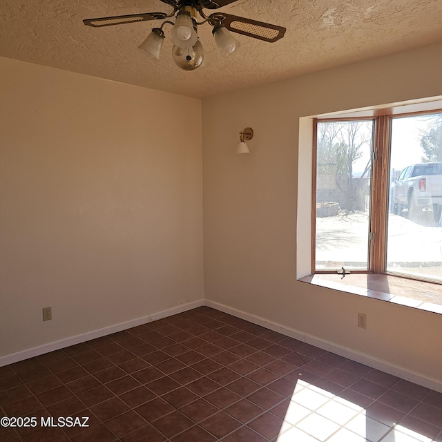 unfurnished room featuring a textured ceiling, dark tile patterned floors, and ceiling fan