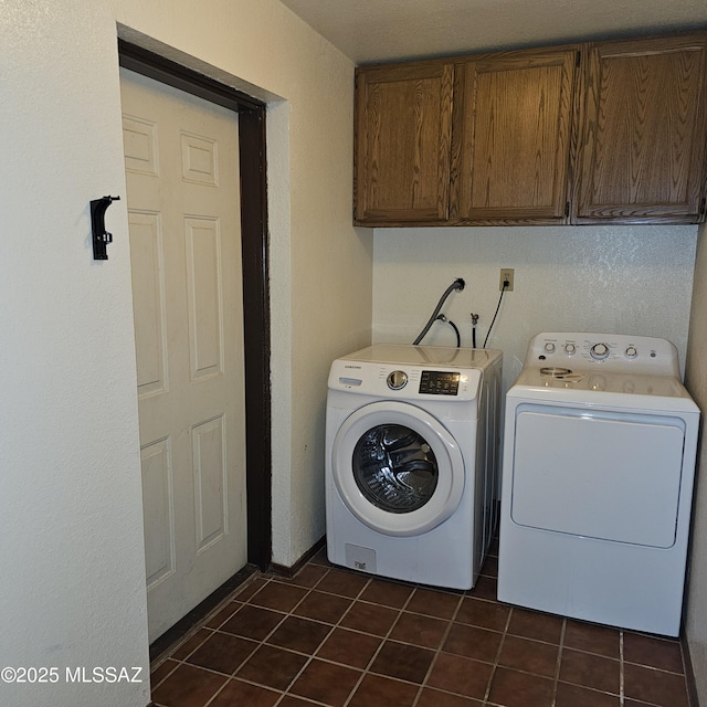 laundry area with cabinets, washing machine and clothes dryer, and dark tile patterned flooring