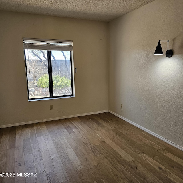 empty room featuring wood-type flooring and a textured ceiling