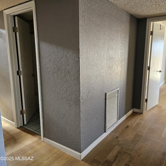 corridor featuring a textured ceiling and light hardwood / wood-style flooring