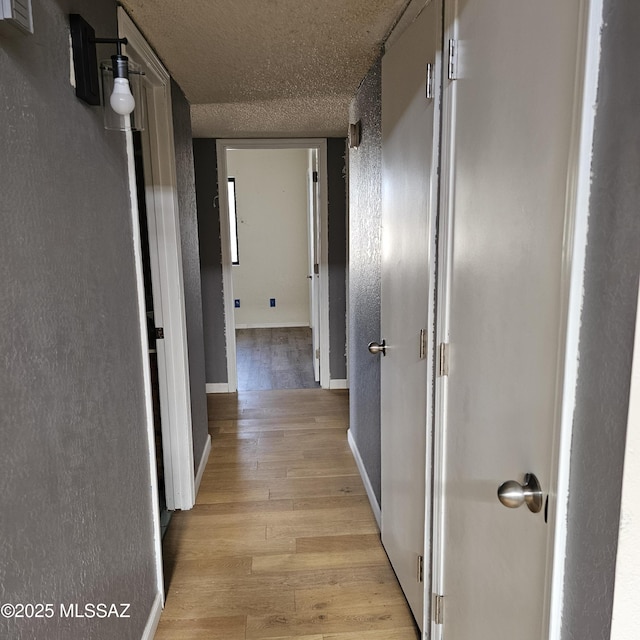 hallway featuring light hardwood / wood-style floors and a textured ceiling