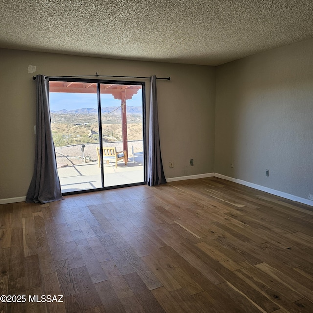 unfurnished room featuring a mountain view, hardwood / wood-style floors, and a textured ceiling