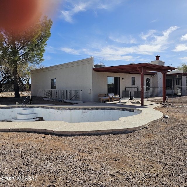 back of house featuring an empty pool and a patio area