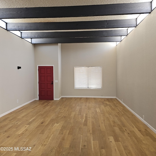 unfurnished room featuring beamed ceiling and light wood-type flooring