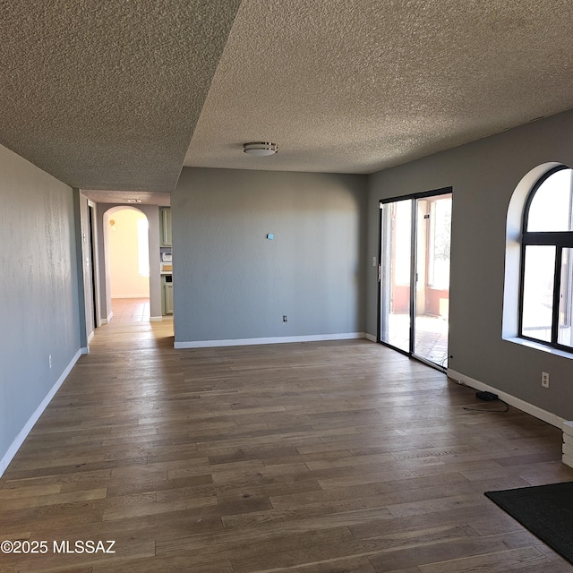 spare room featuring dark wood-type flooring and a textured ceiling