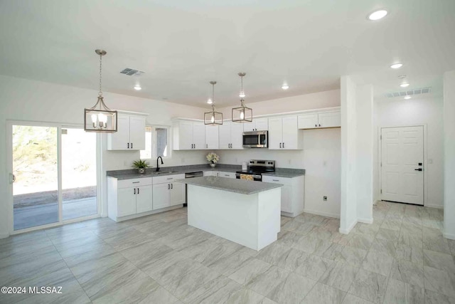 kitchen with sink, a kitchen island, pendant lighting, white cabinets, and appliances with stainless steel finishes