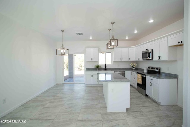 kitchen with white cabinets, decorative light fixtures, stainless steel appliances, and a kitchen island