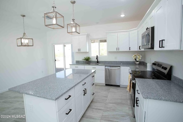 kitchen featuring white cabinets, appliances with stainless steel finishes, a center island, and decorative light fixtures