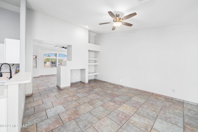 unfurnished living room with ceiling fan, sink, and high vaulted ceiling