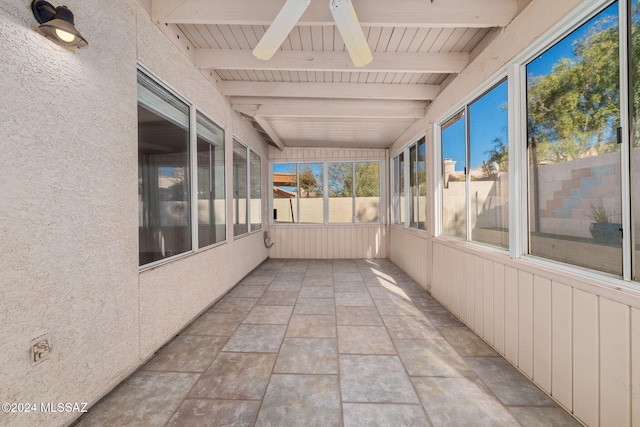 unfurnished sunroom featuring beamed ceiling and ceiling fan