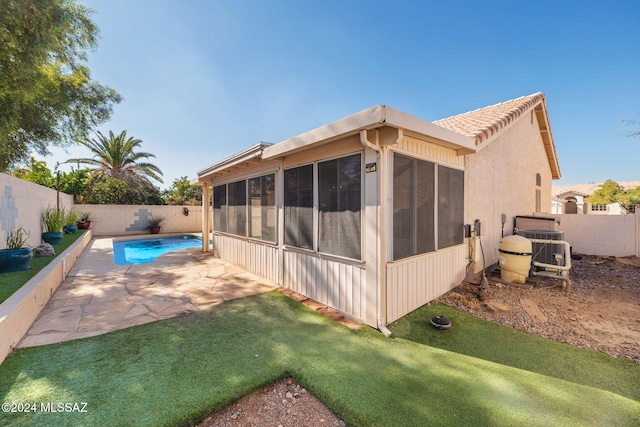 back of house featuring a sunroom, a fenced in pool, a patio, and central AC