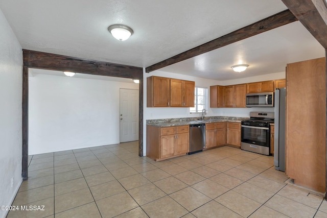 kitchen featuring light tile patterned flooring, beamed ceiling, stainless steel appliances, and a textured ceiling