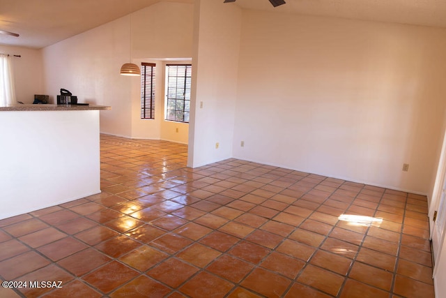 tiled spare room featuring vaulted ceiling and ceiling fan