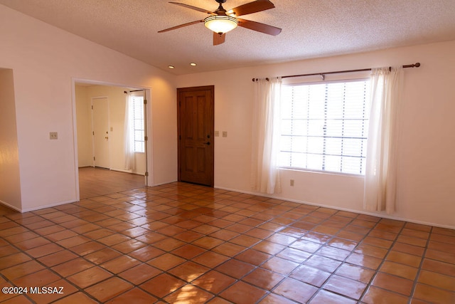 tiled spare room with a textured ceiling, vaulted ceiling, and ceiling fan