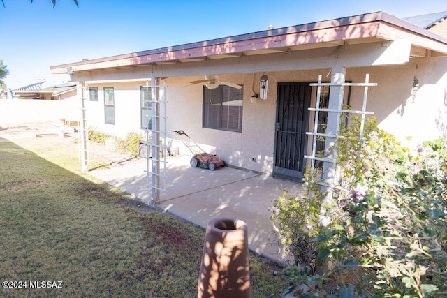 rear view of property with a patio area, ceiling fan, and a yard