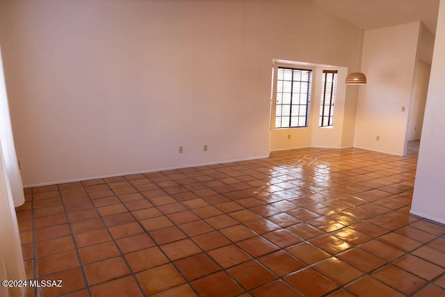 unfurnished room featuring dark tile patterned flooring and high vaulted ceiling