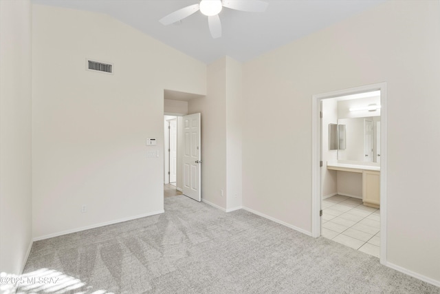 spare room featuring light carpet, vaulted ceiling, and ceiling fan