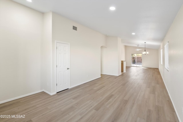 unfurnished room with light hardwood / wood-style floors, a chandelier, and vaulted ceiling