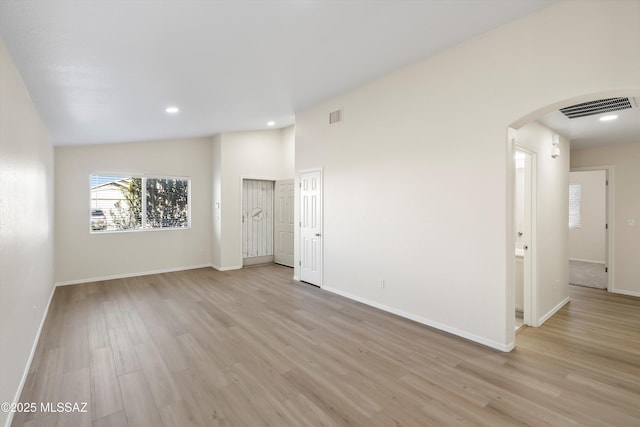 unfurnished room with light wood-type flooring and lofted ceiling