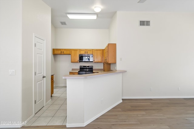 kitchen with kitchen peninsula, light tile patterned floors, and electric stove