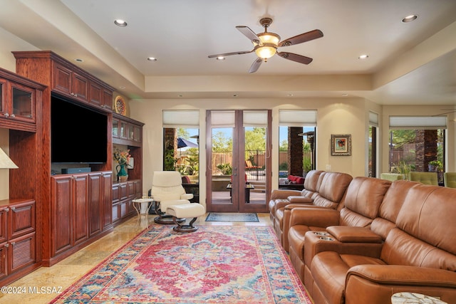 living room featuring ceiling fan, a raised ceiling, and french doors