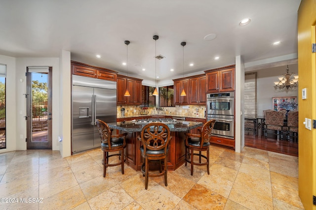 kitchen with tasteful backsplash, dark stone counters, decorative light fixtures, a kitchen island, and appliances with stainless steel finishes