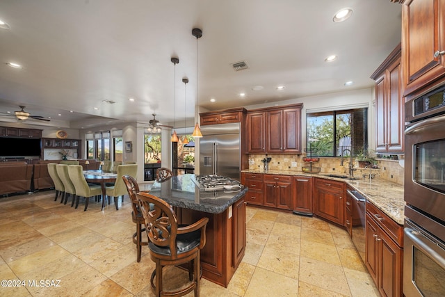 kitchen with a wealth of natural light, a kitchen island, sink, and appliances with stainless steel finishes