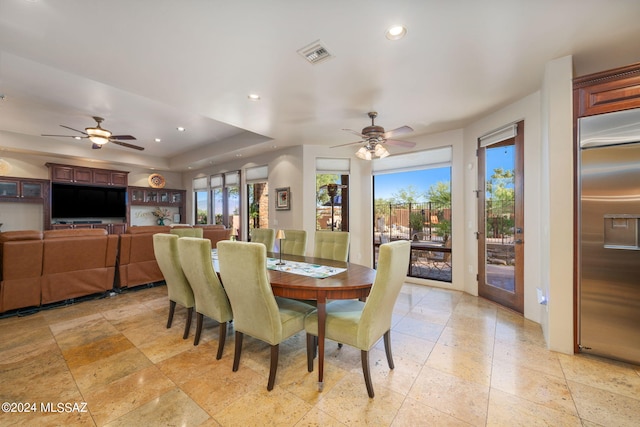 dining space featuring a raised ceiling and ceiling fan