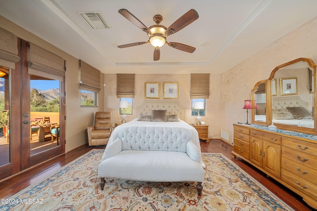 bedroom with a raised ceiling, ceiling fan, dark hardwood / wood-style flooring, and access to outside