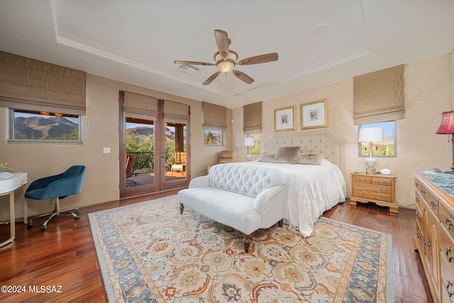 bedroom featuring a tray ceiling, access to exterior, ceiling fan, and dark wood-type flooring