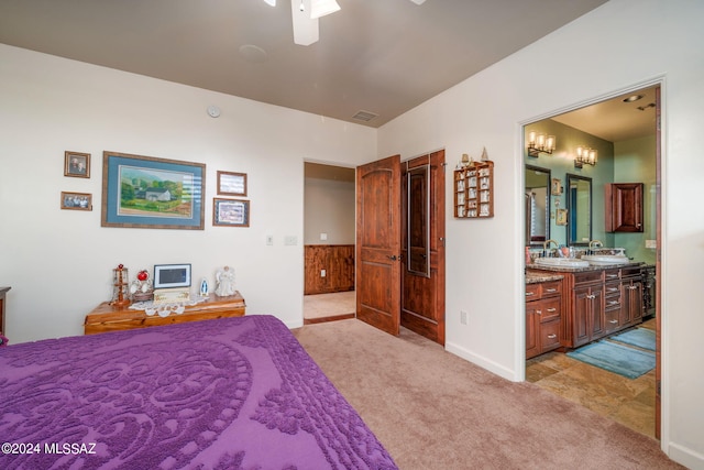 bedroom featuring ceiling fan, sink, light colored carpet, and ensuite bathroom