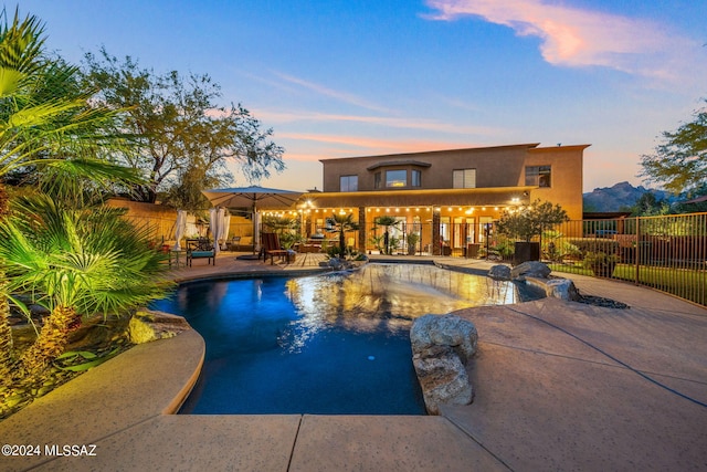 pool at dusk featuring a mountain view and a patio area