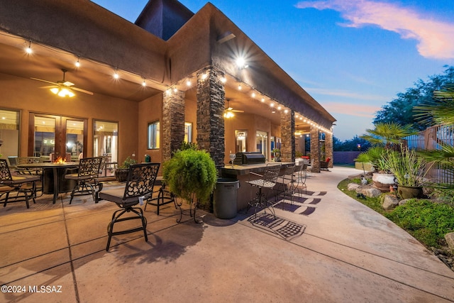 patio terrace at dusk with ceiling fan and exterior bar