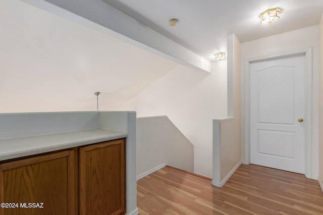 corridor featuring beam ceiling and light hardwood / wood-style floors