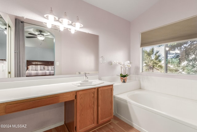 bathroom with hardwood / wood-style floors, vanity, lofted ceiling, ceiling fan, and a tub to relax in