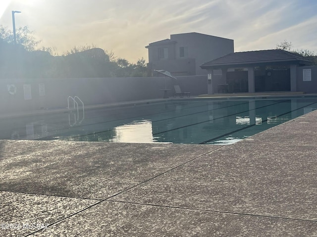 pool at dusk featuring a patio