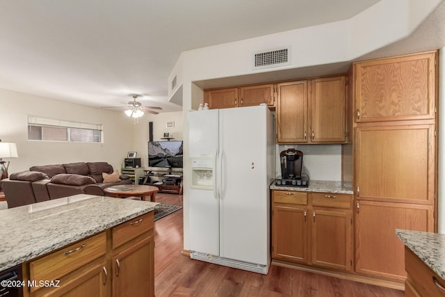 kitchen with dark wood-type flooring, ceiling fan, decorative backsplash, white fridge with ice dispenser, and light stone counters