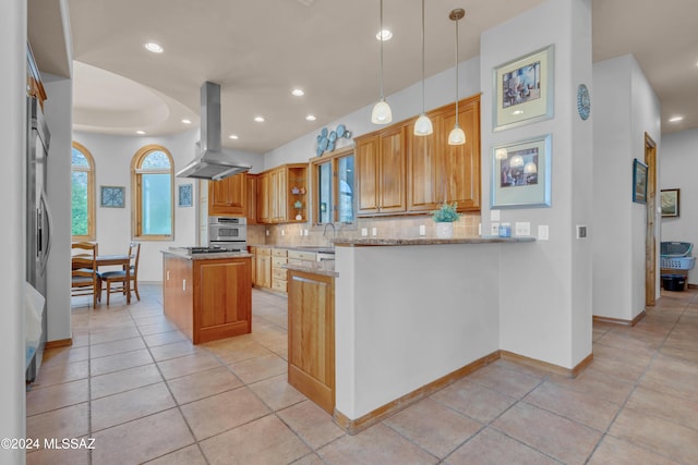 kitchen with light stone counters, backsplash, kitchen peninsula, pendant lighting, and island range hood