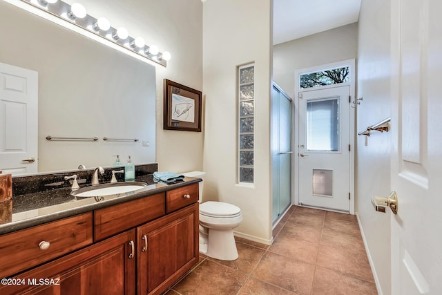 bathroom with tile patterned floors, vanity, toilet, and a shower with shower door