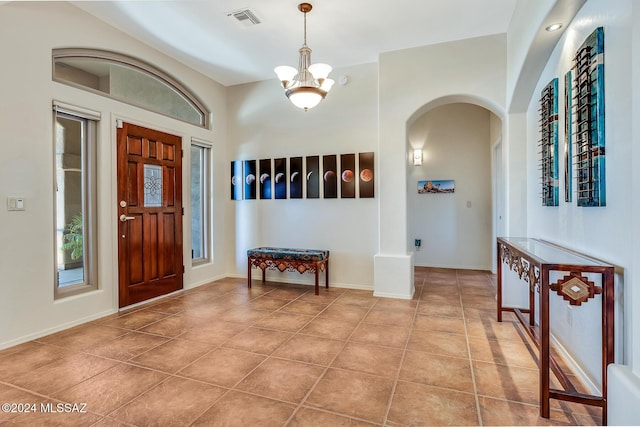 tiled foyer entrance featuring a chandelier