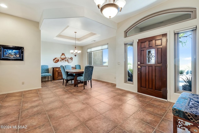 foyer featuring a raised ceiling, tile patterned floors, and a chandelier