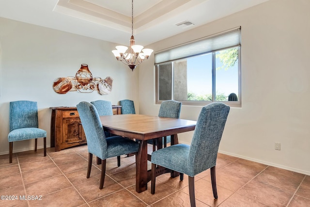 tiled dining space featuring a raised ceiling and an inviting chandelier