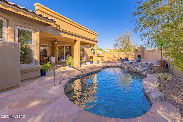 view of pool featuring pool water feature, exterior fireplace, a patio area, and ceiling fan