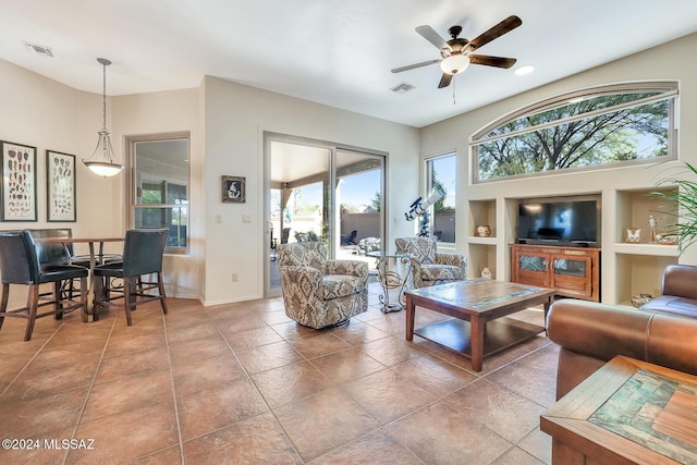 living room with built in shelves, tile patterned floors, a wealth of natural light, and ceiling fan