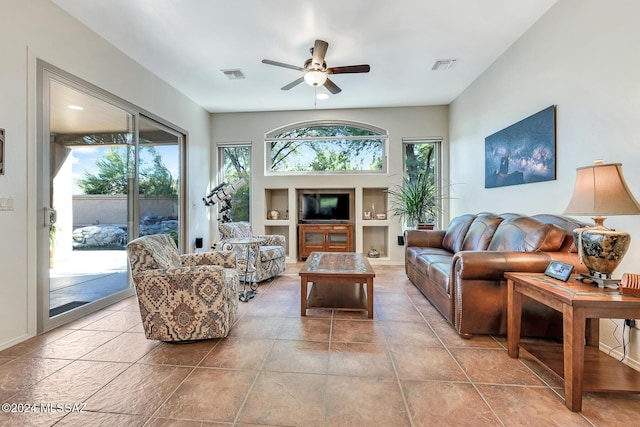 tiled living room featuring built in features, ceiling fan, and a healthy amount of sunlight