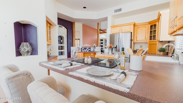 kitchen featuring kitchen peninsula, light brown cabinetry, sink, and stainless steel refrigerator with ice dispenser